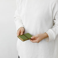 Person holding a green wallet against a plain background